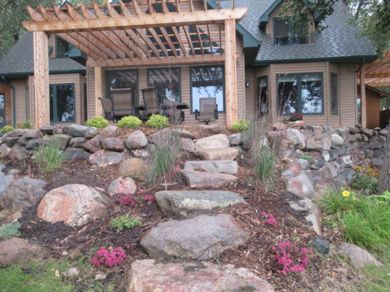 Read more about the article Beautiful Natural Landscaping- Pergola, Wood Look Paver, Boulder Walls, Stone Steps